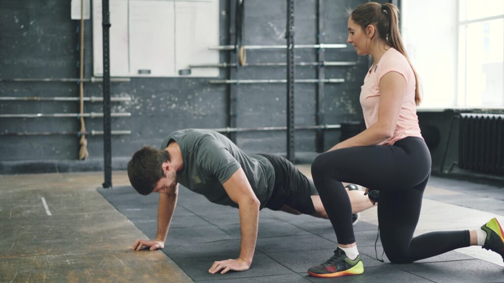 Man doing push-ups with a trainer spotting him.